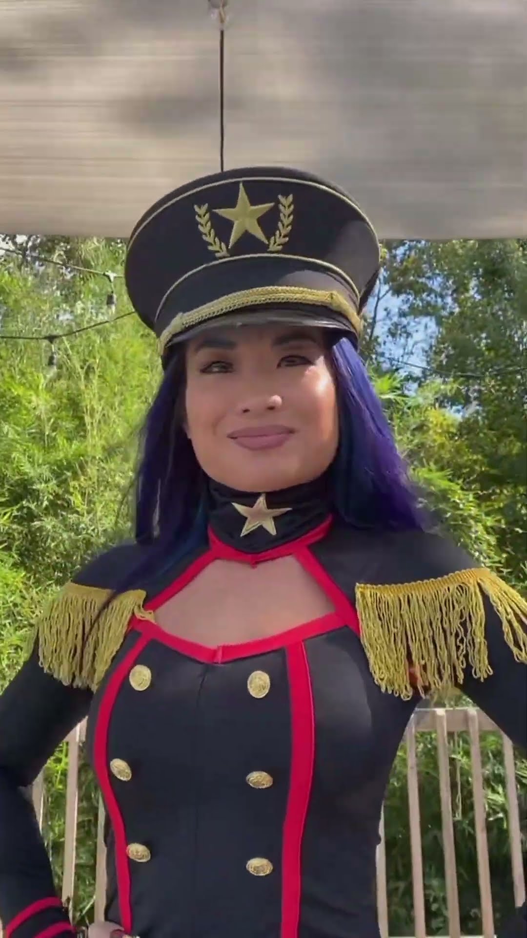 Katie in a black and red military-style costume and cap, smiling