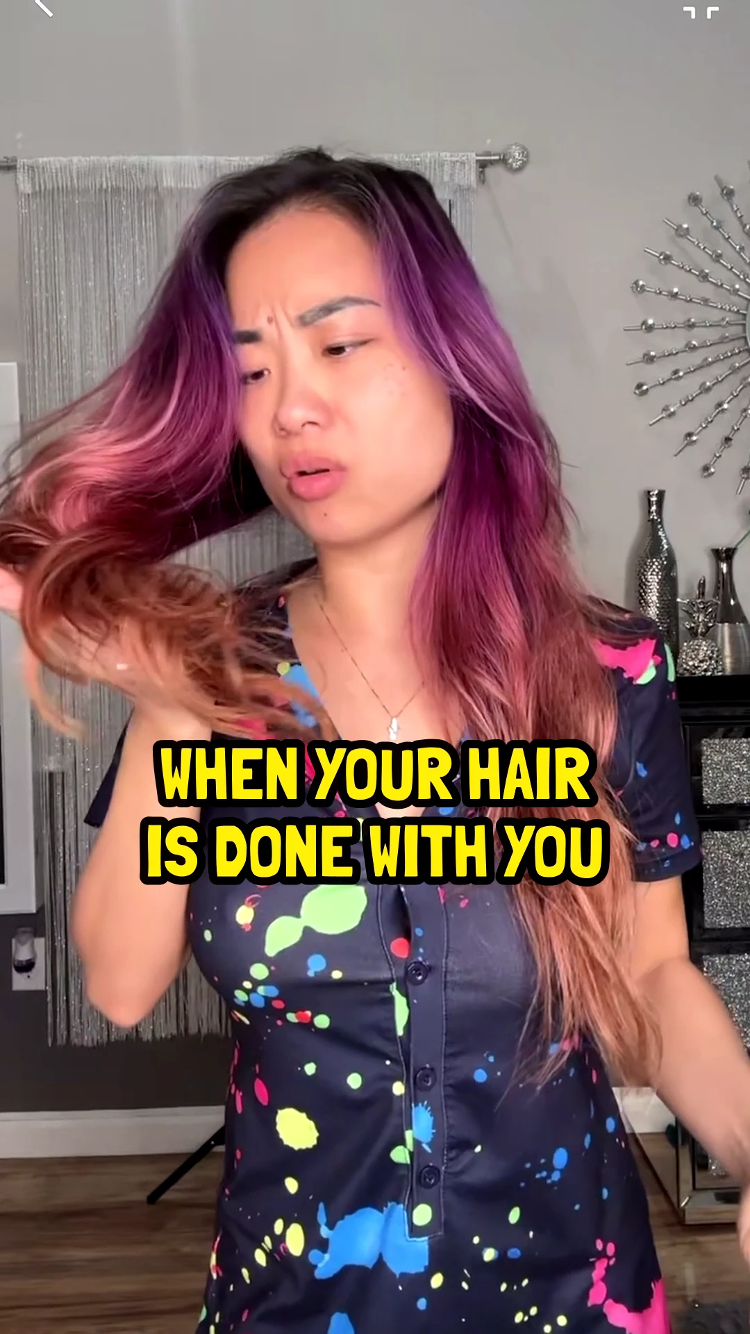 Katie with purple and pink hair, frowning at the ends of it