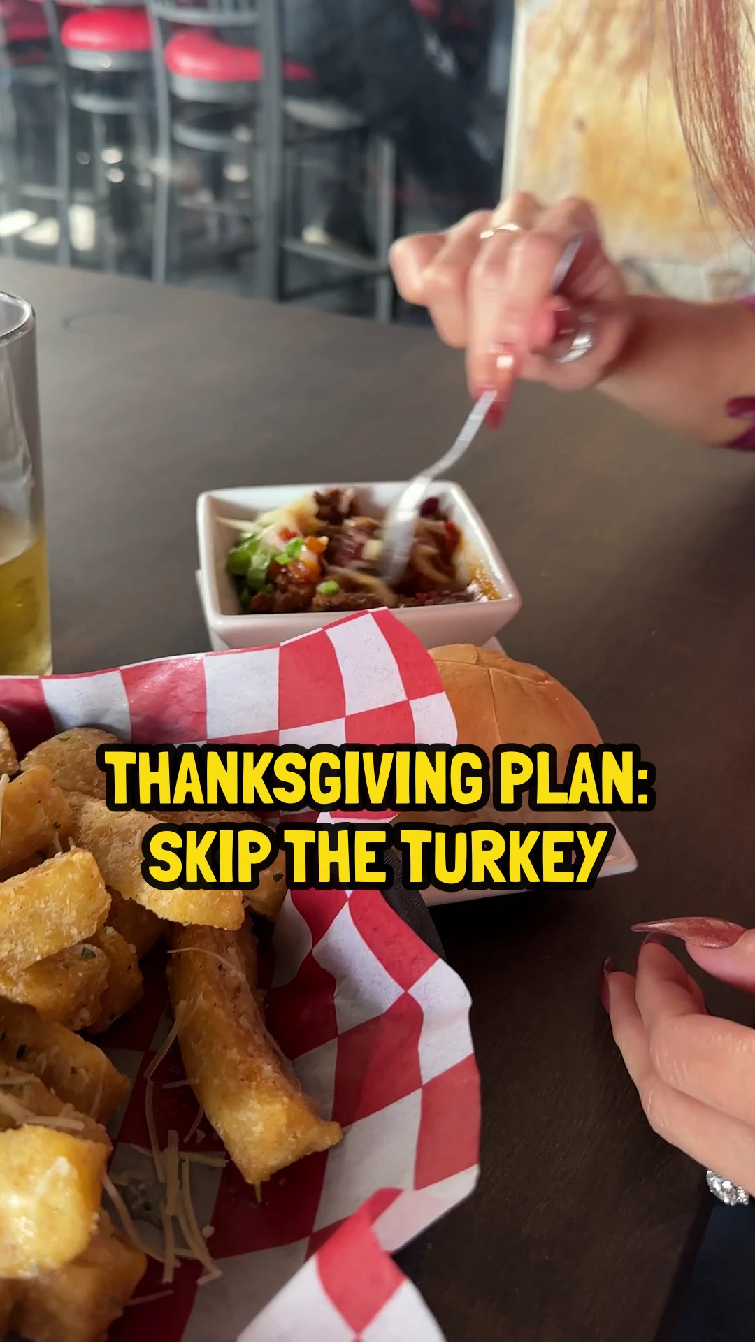 Fork digging into a bowl of chili next to a basket of fried yuca fries