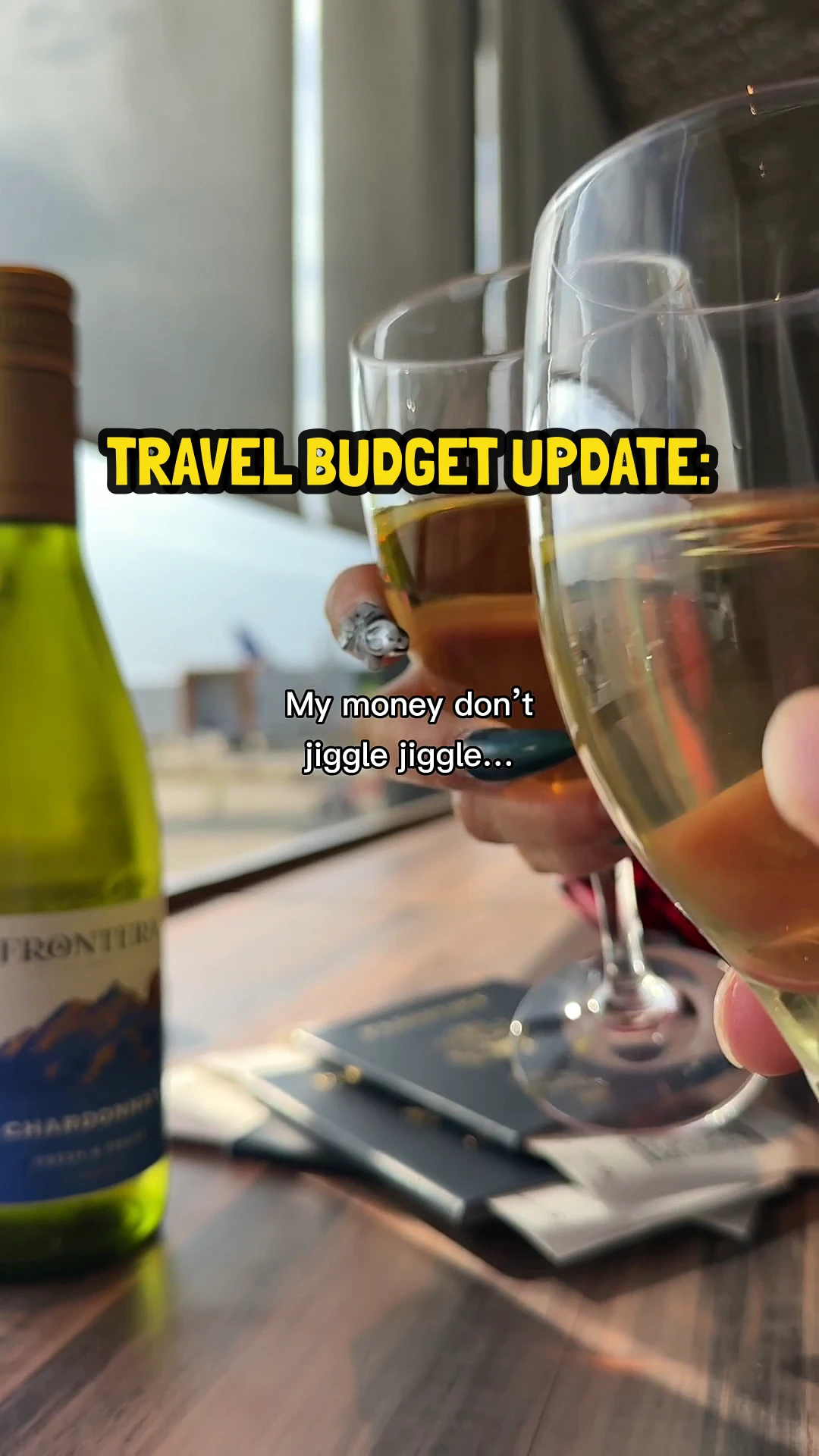 Two wine glasses clinking in front of a bottle of Chardonnay and passports